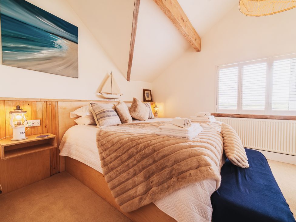 A bedroom with a bed and window at Glanllyn Bach in Llanfaelog