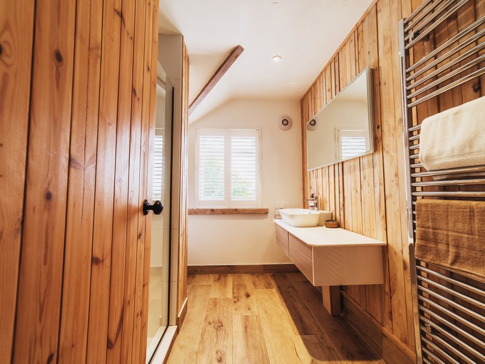 A bathroom with a shower, sink, and towel rail at Glanllyn Bach in Llanfaelog