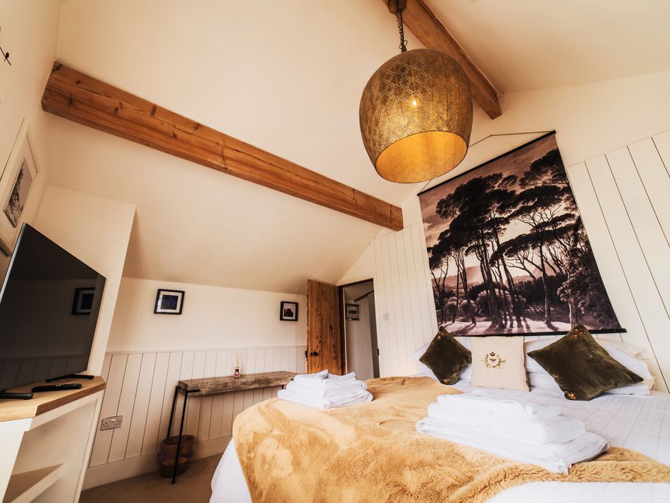 A bedroom with a bed and television at Glanllyn Bach in Llanfaelog