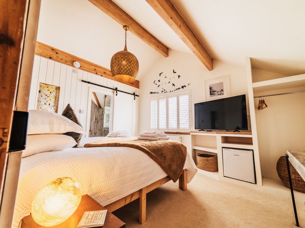 A bedroom with a bed and television at Glanllyn Bach in Llanfaelog