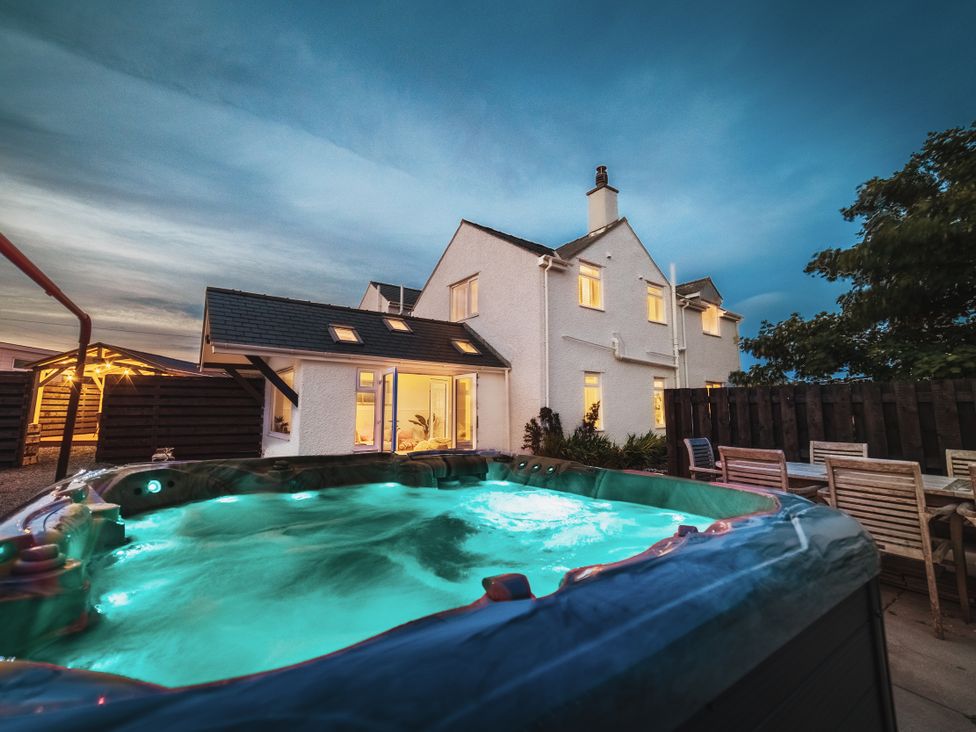 An outdoor area with a hot tub and house at Glanllyn Bach Llanfaelog