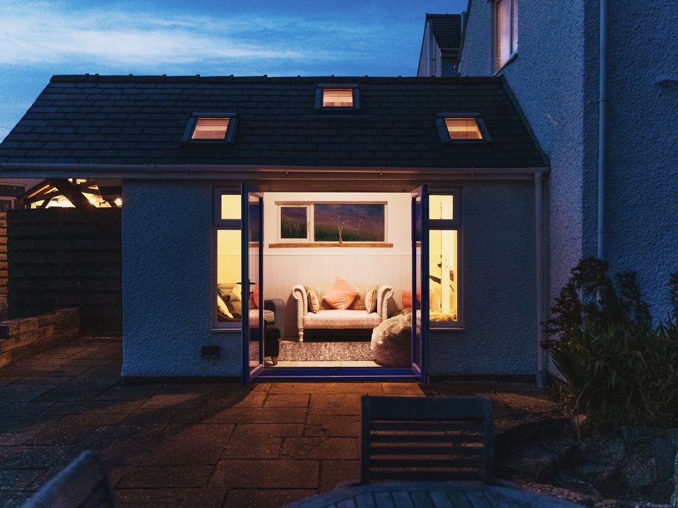 A living room with a couch visible from the patio at Glanllyn Bach Llanfaelog
