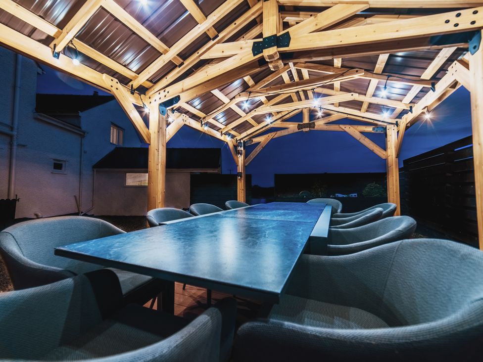 An outdoor dining area with a wooden structure and table at Glanllyn Bach in Llanfaelog