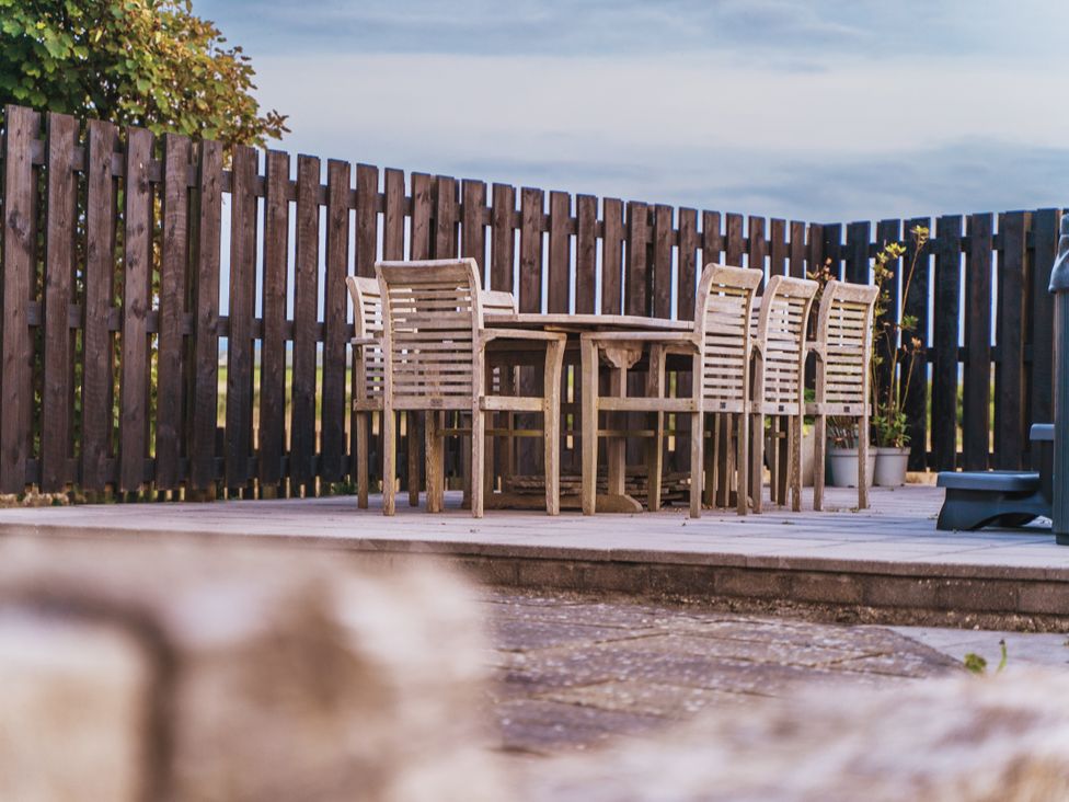 An outdoor dining area with a table and chairs at Glanllyn Bach in Llanfaelog