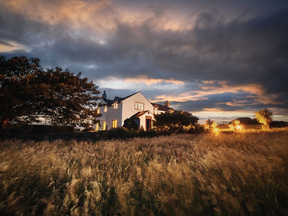 A house at sunset with grass and trees at Glanllyn Bach Llanfaelog