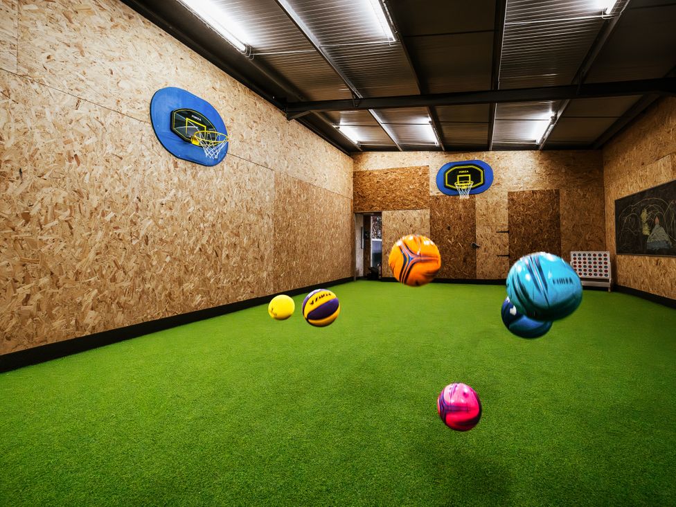 A playroom with a basketball hoop and colorful balls at Glanllyn Bach in Llanfaelog