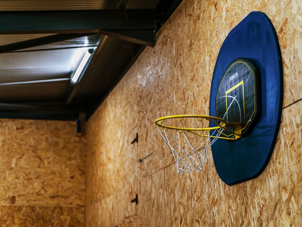 A basketball hoop and backboard mounted on a wall in an indoor sports area at Glanllyn Bach in Llanfaelog