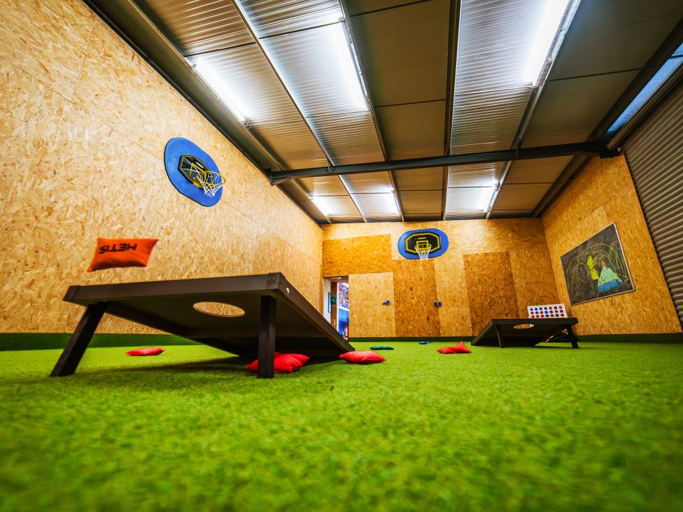 A game room with cornhole boards and a basketball hoop at Glanllyn Bach in Llanfaelog