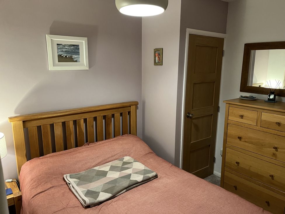A bedroom with a wooden bed and dresser at The Lobster Pot in Oxwich