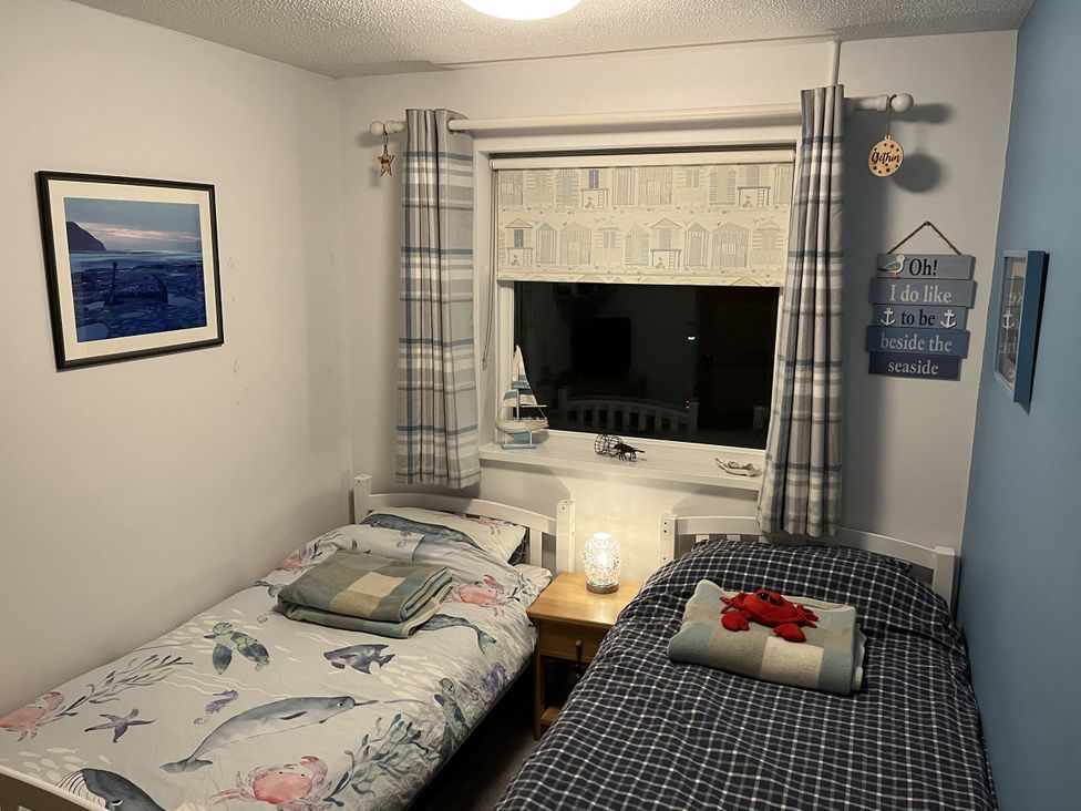 A bedroom with two beds and a window at The Lobster Pot in Oxwich