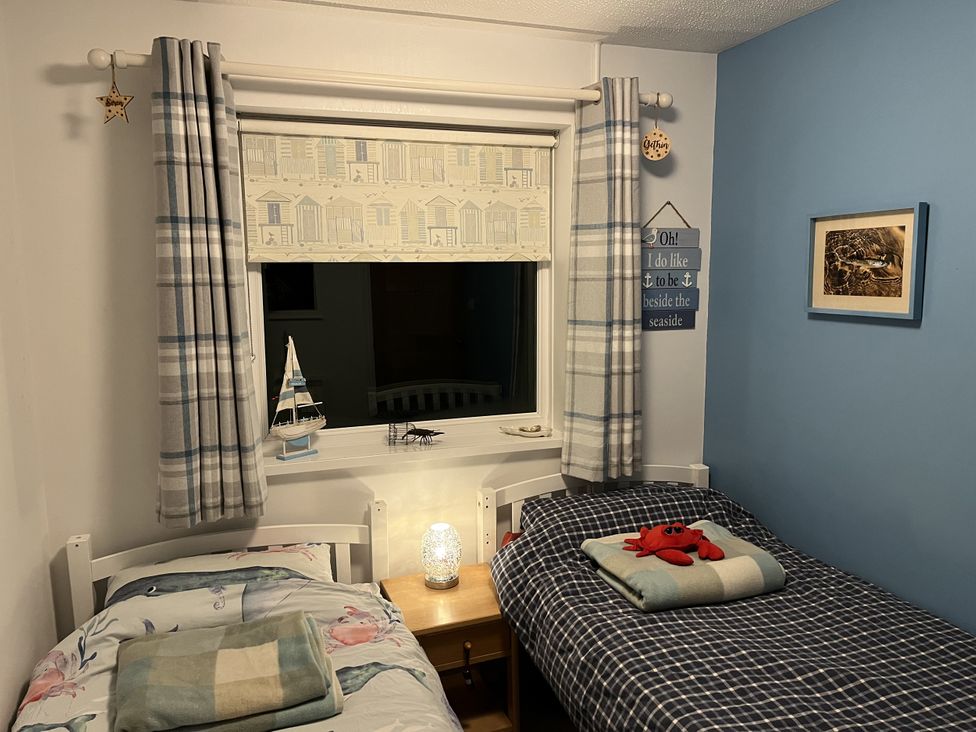 A bedroom with two beds and a window at The Lobster Pot in Oxwich