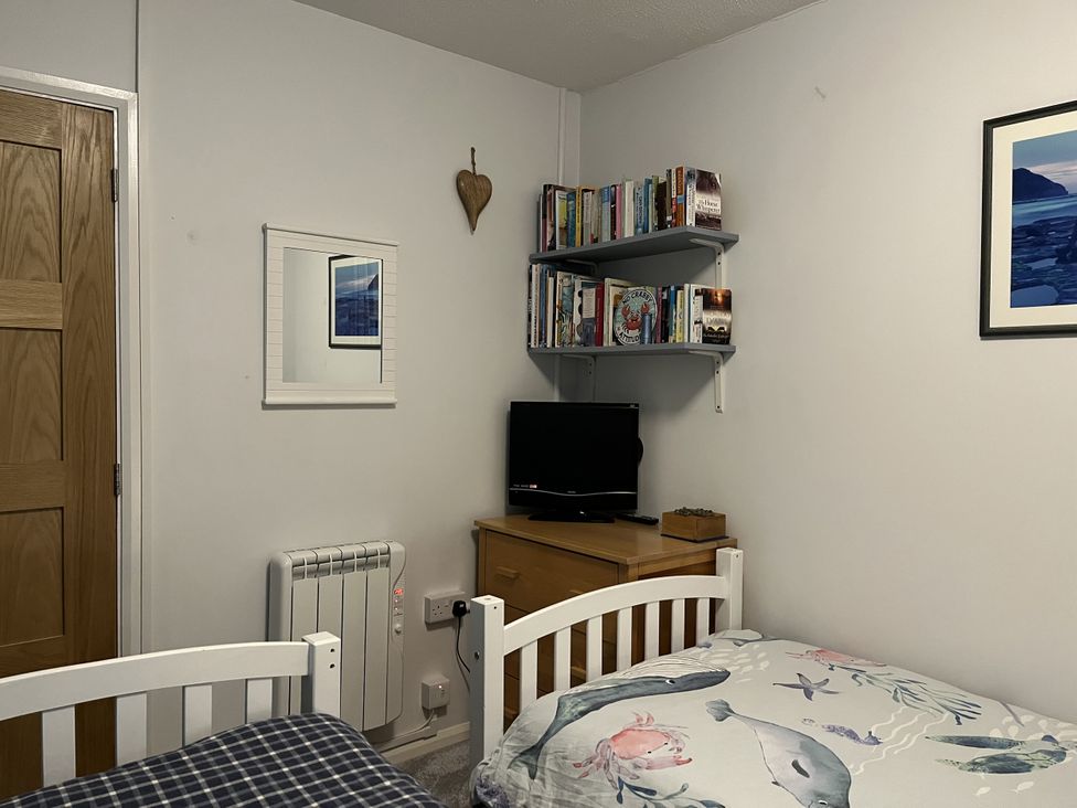 A bedroom with beds and a shelf of books at The Lobster Pot in Oxwich