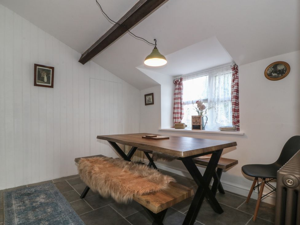 A dining room with a wooden table and benches at Tan Y Merddyn in Ceunant near Llanrug