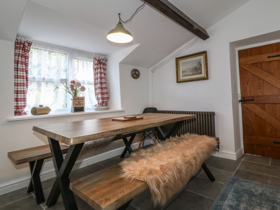 A dining room with a wooden table and benches at Tan Y Merddyn in Ceunant near Llanrug