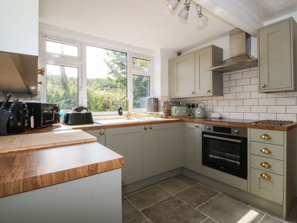 A kitchen with cabinets, oven, and sink at Tan Y Merddyn near Ceunant near Llanrug