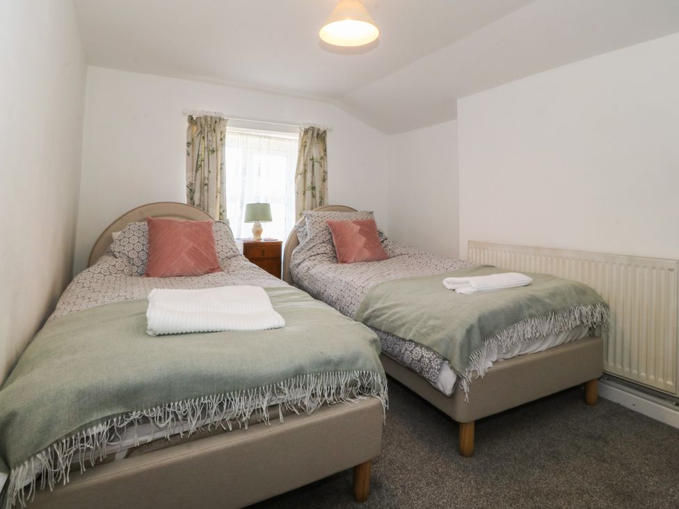 A bedroom with two beds nightstand and lamp at Tan Y Merddyn in Ceunant near Llanrug