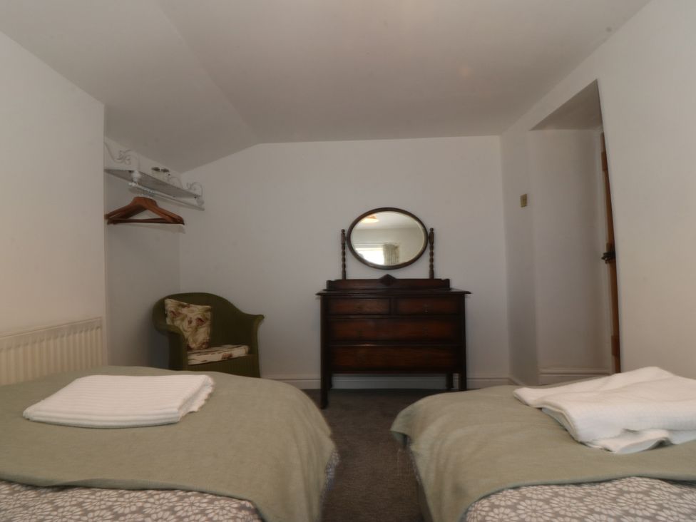 A bedroom with two beds, a chair, a dresser and a mirror at Tan Y Merddyn Ceunant near Llanrug
