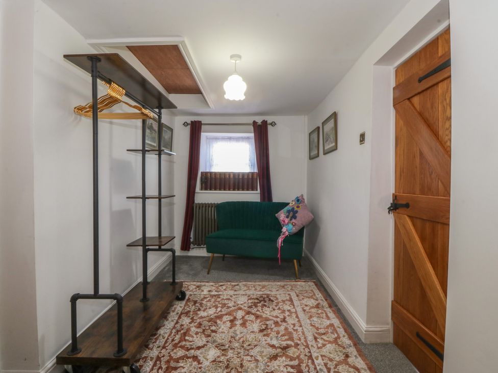 An entryway with a sofa and coat rack at Tan Y Merddyn in Ceunant near Llanrug