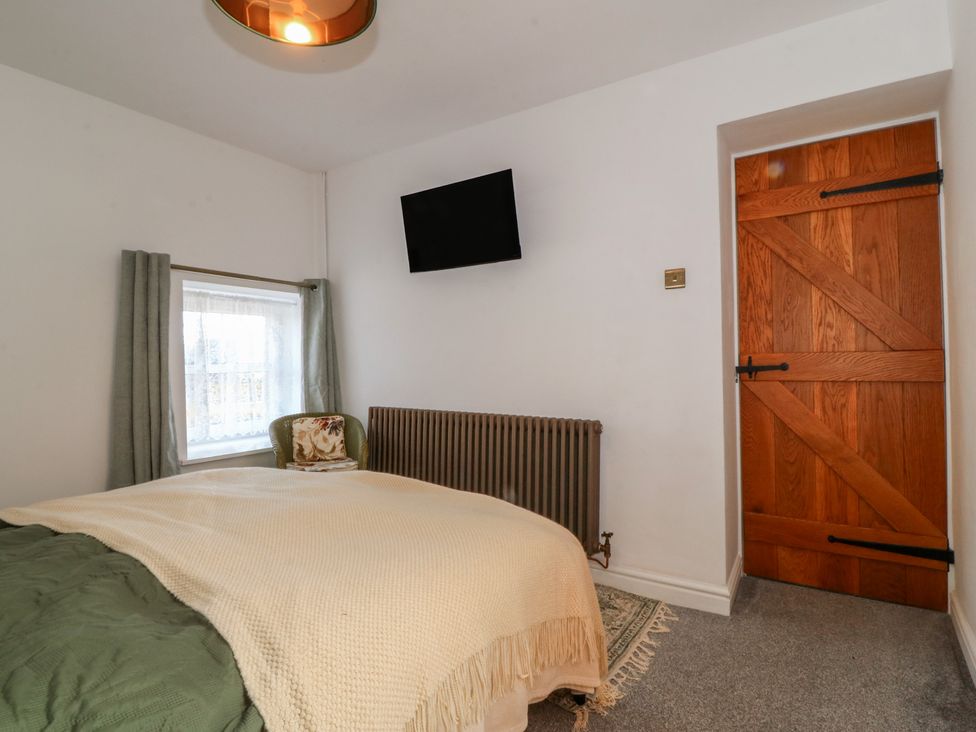 A bedroom with a bed and a television at Tan Y Merddyn Ceunant near Llanrug