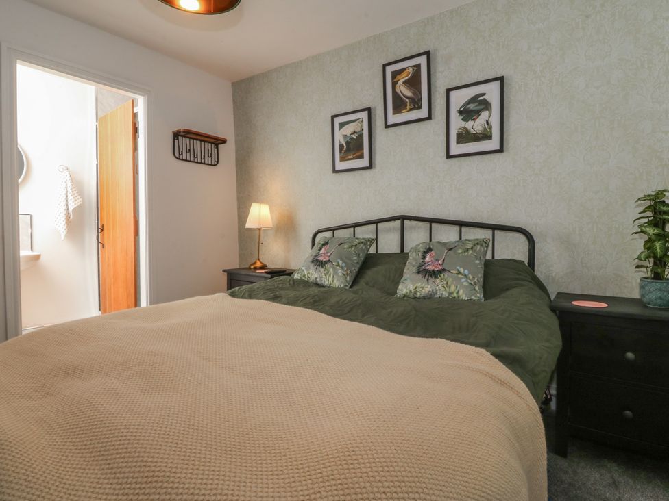 A bedroom with a bed and lamp at Tan Y Merddyn Ceunant near Llanrug