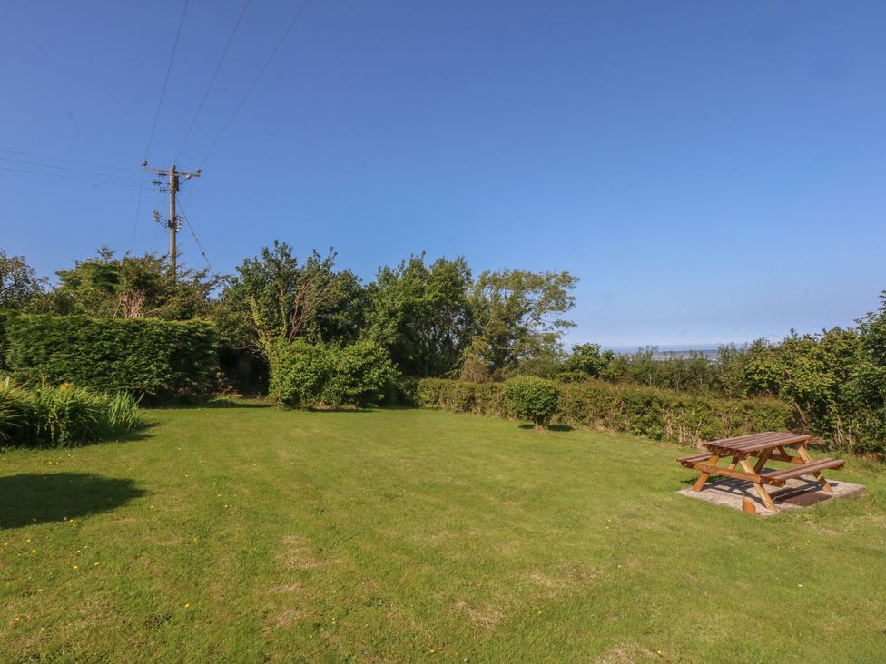 A garden with a picnic table and trees at Tan Y Merddyn in Ceunant near Llanrug