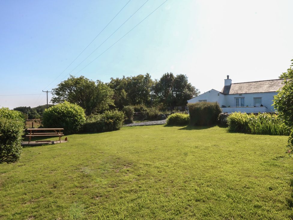 A garden with a bench and house at Tan Y Merddyn Ceunant near Llanrug