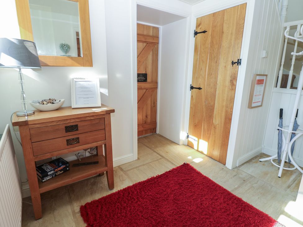 A hallway with a table, lamp, and mirror at Parr Cottage Snape near Bedale