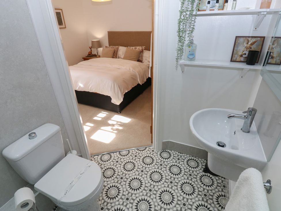 A bathroom with a toilet and sink leading to a bedroom at Parr Cottage Snape near Bedale