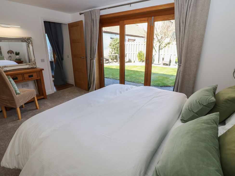 A bedroom with a bed and a mirror at The Cart House Snape near Bedale