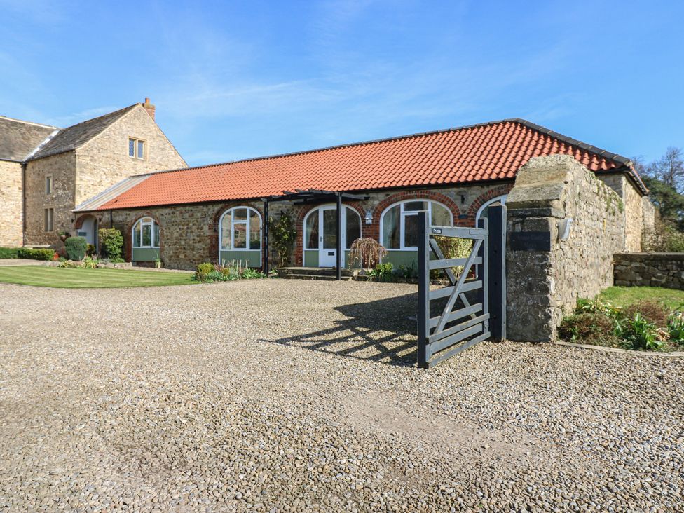 A building with a gravel driveway and garden at The Cart House in Snape near Bedale