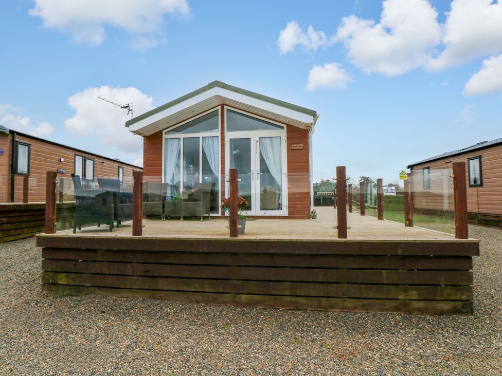 A cabin with a deck and glass railing at Gentle Tide near Hasguard Cross