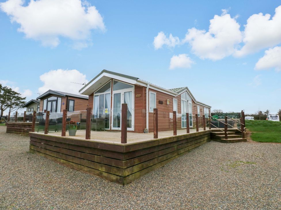 A wooden lodge with decking and steps at Gentle Tide in Hasguard Cross near Little Haven