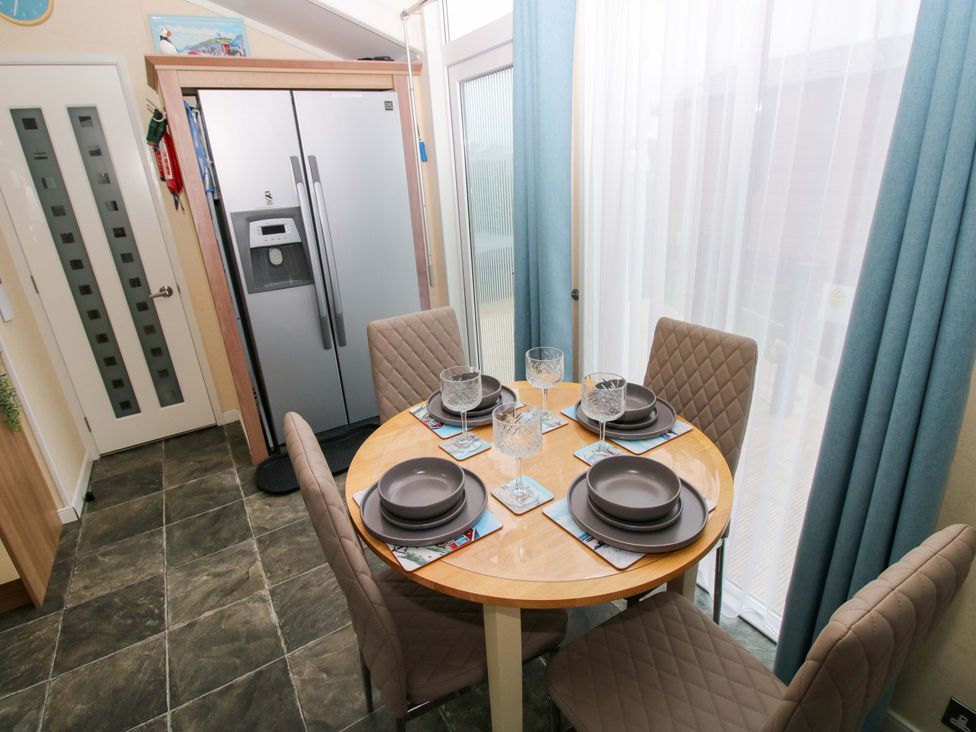 A kitchen with a dining table and refrigerator at Gentle Tide Hasguard Cross near Little Haven
