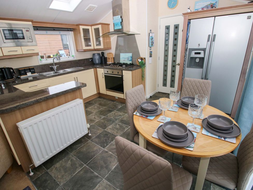 A kitchen with a dining table and appliances at Gentle Tide Hasguard Cross near Little Haven