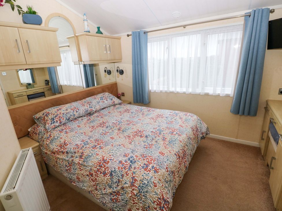 A bedroom with a bed and wardrobe at Gentle Tide Hasguard Cross near Little Haven