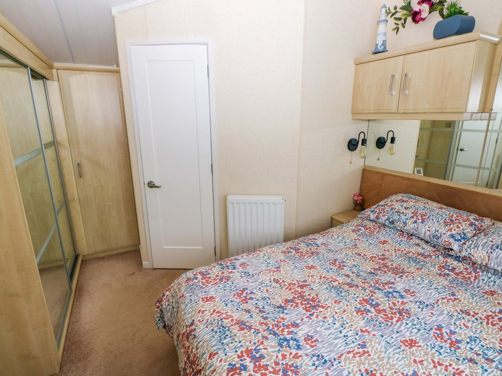 A bedroom with a bed and wardrobe at Gentle Tide Hasguard Cross near Little Haven