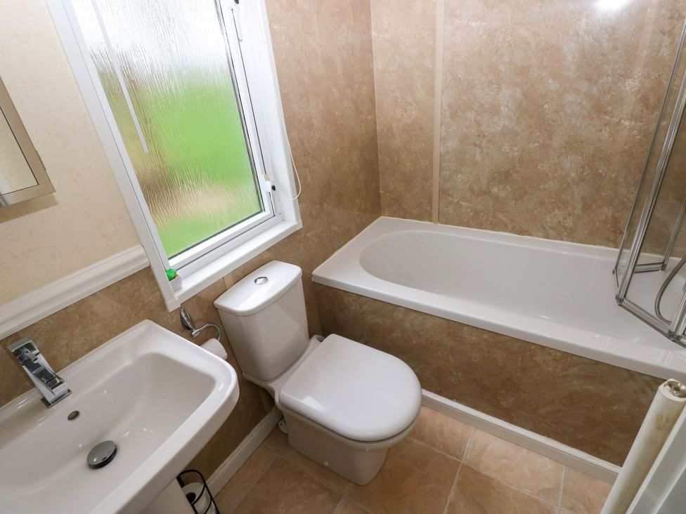 A bathroom with a tub, toilet, and sink at Gentle Tide Hasguard Cross near Little Haven