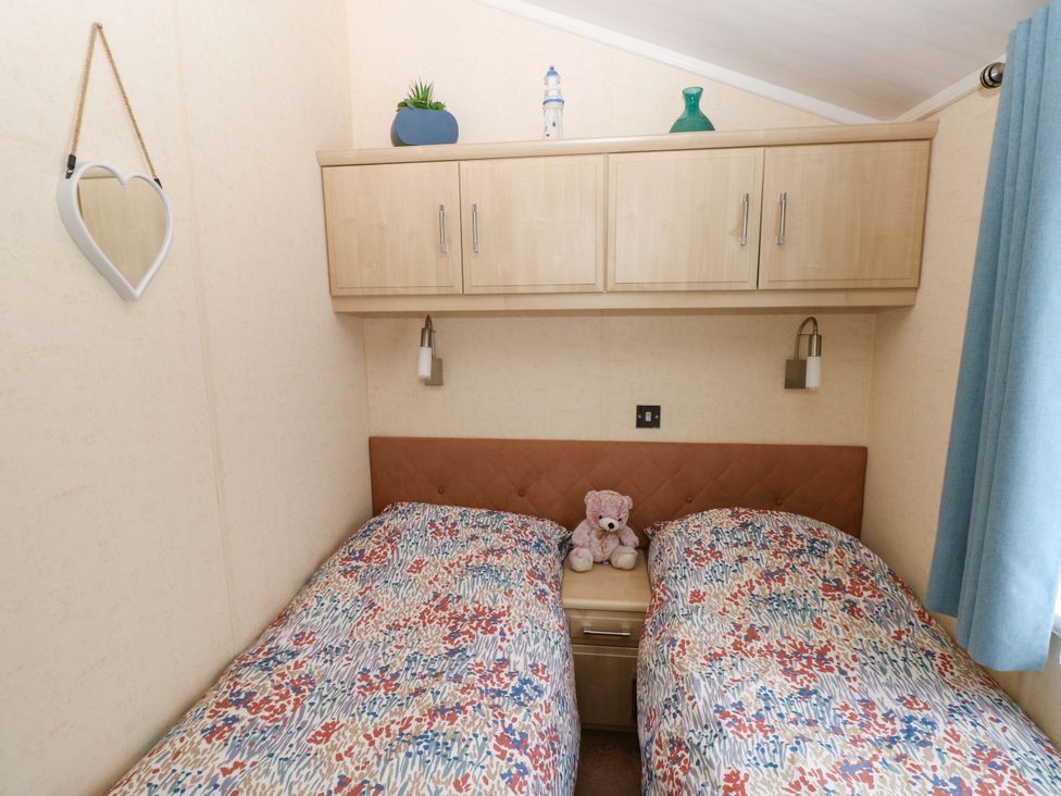 A bedroom with two beds and a mirror at Gentle Tide Hasguard Cross near Little Haven