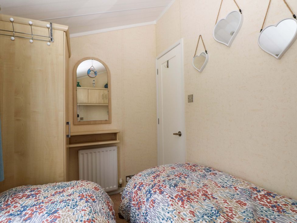 A bedroom with two beds and a mirror at Gentle Tide in Hasguard Cross near Little Haven