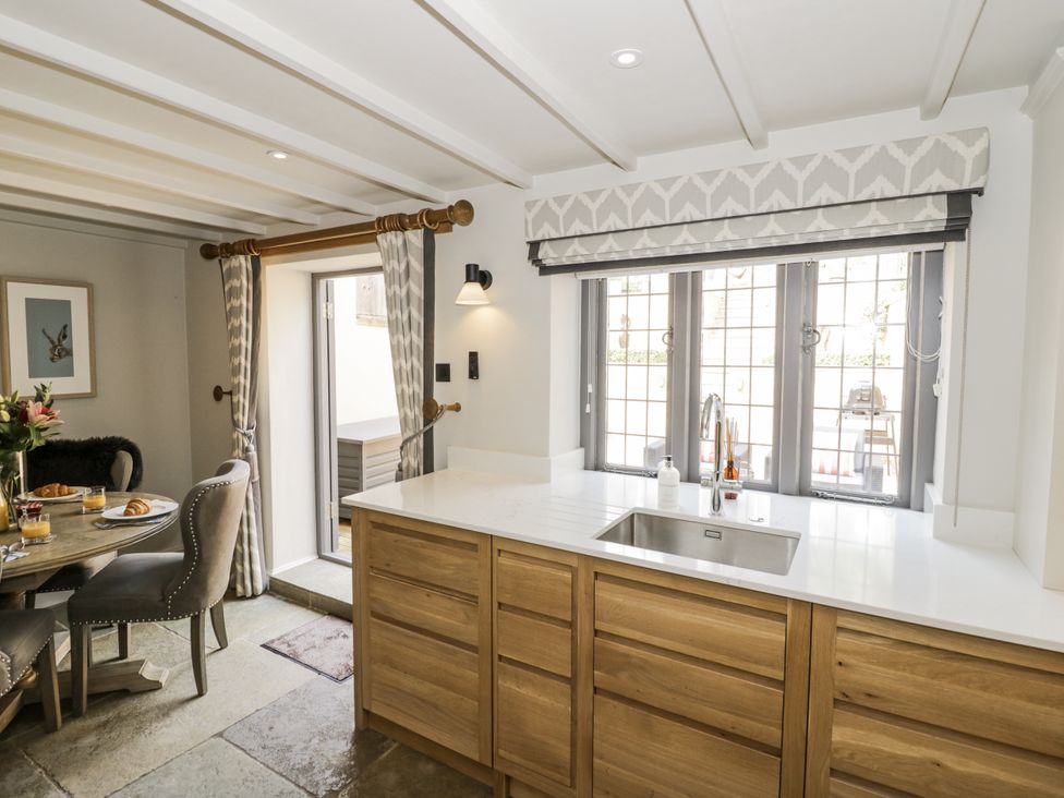 A kitchen with a sink and dining table at Cotstone Cottage in Chipping Campden
