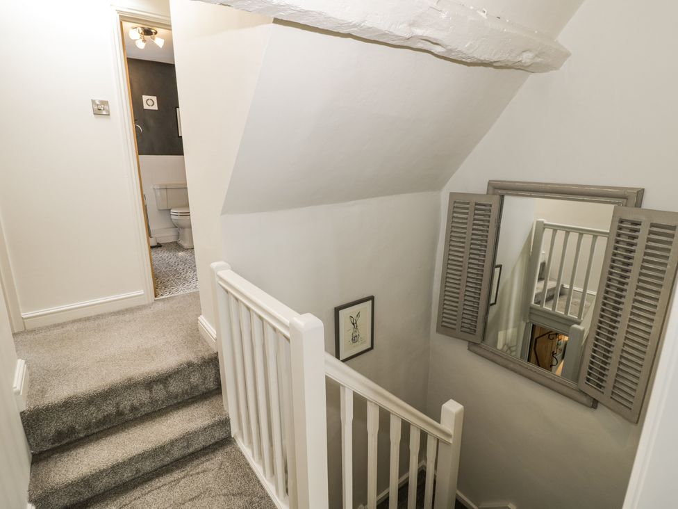 A hallway with a staircase and a mirror at Cotstone Cottage Chipping Campden