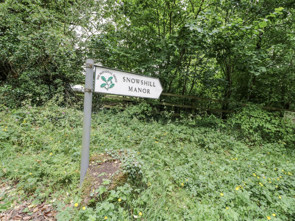 A sign for Snowshill Manor surrounded by foliage at Cotstone Cottage in Chipping Campden