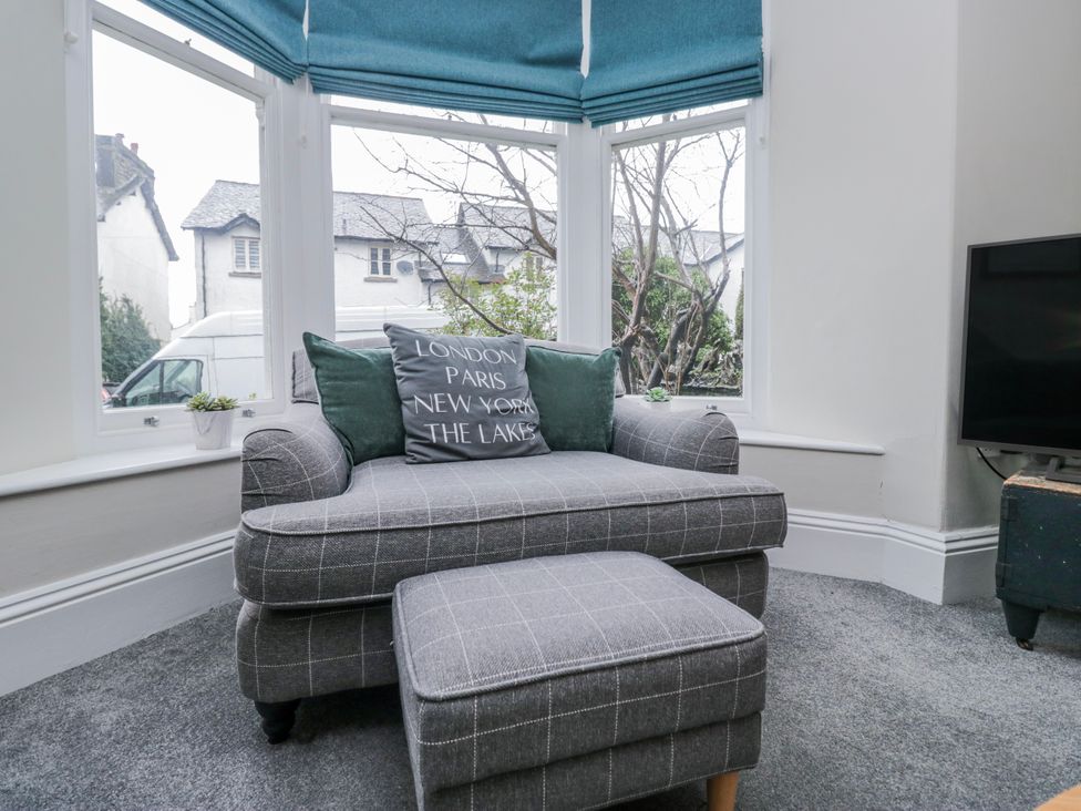 A living room with an armchair and ottoman at The Thistles Bowness-On-Windermere