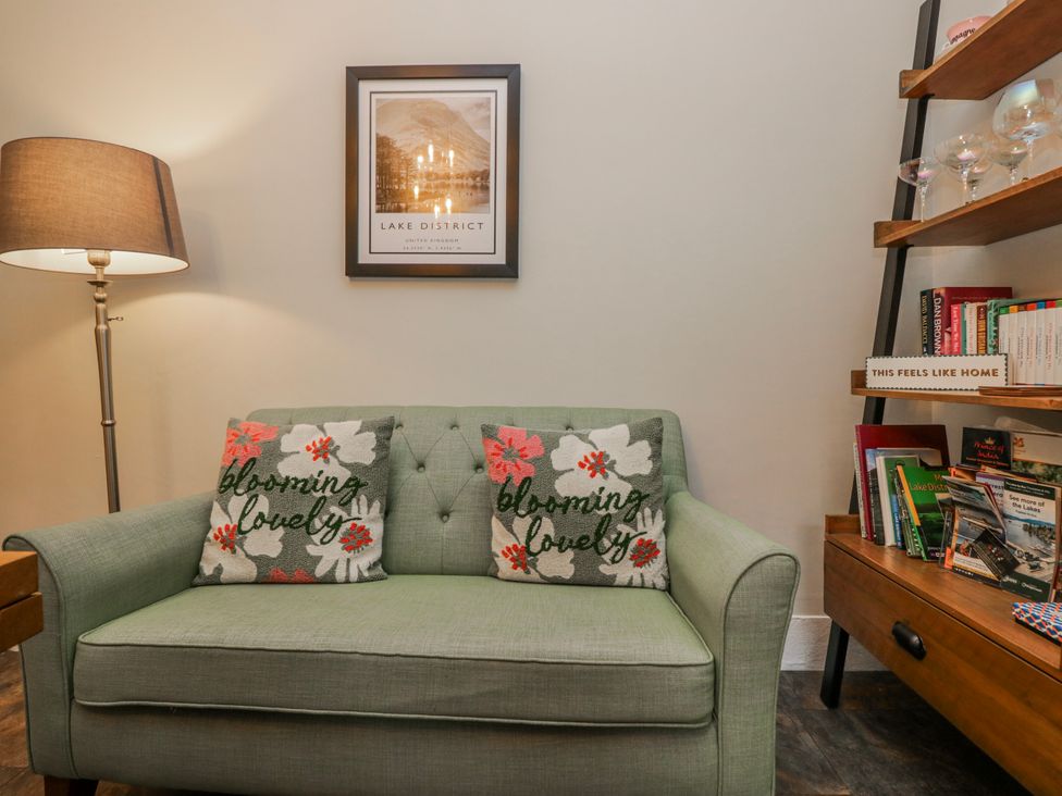 A living room with a sofa and bookshelves at The Thistles in Bowness-On-Windermere