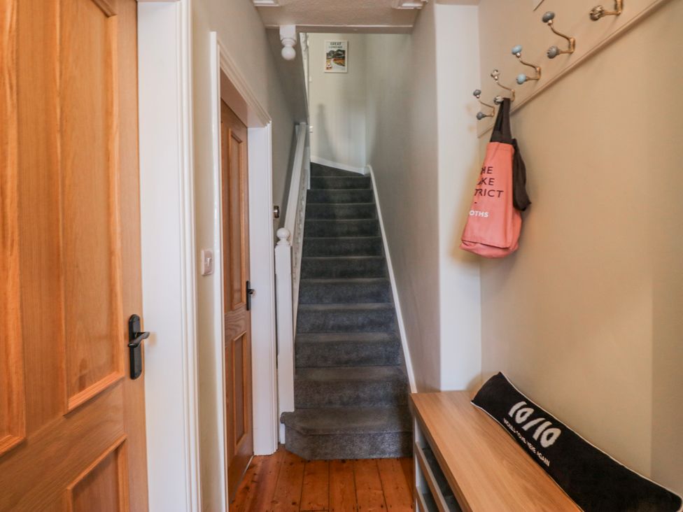 A hallway with a staircase and coat hooks at The Thistles in Bowness-On-Windermere