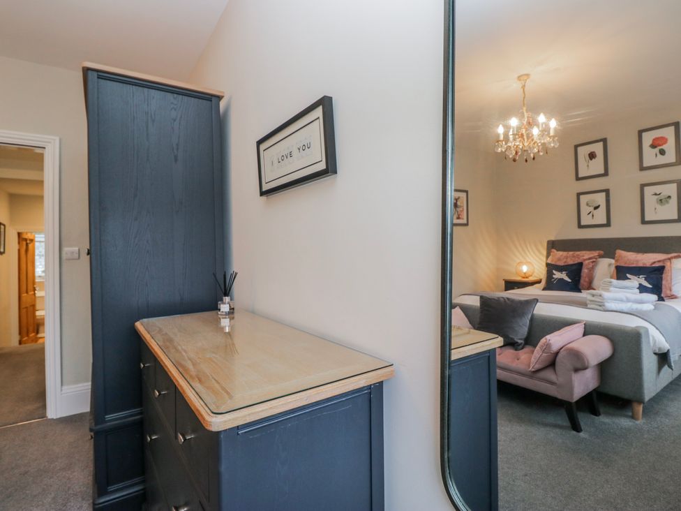 A bedroom with a dresser and mirror at The Thistles in Bowness-On-Windermere