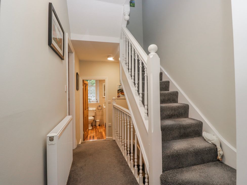 A hallway with a staircase and doorway leading to a bathroom at The Thistles Bowness-On-Windermere