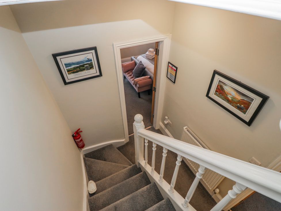 A staircase with a fire extinguisher and paintings at The Thistles in Bowness-On-Windermere