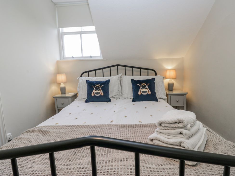 A bedroom with a bed, bedside tables, and lamps at The Thistles in Bowness-On-Windermere