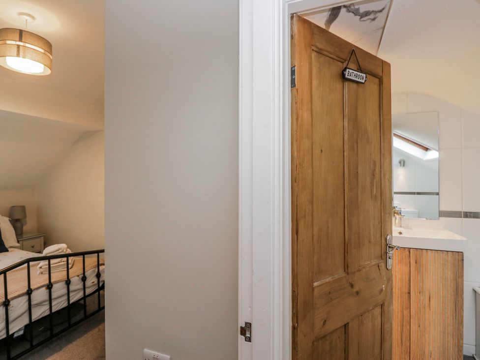 A bathroom entrance with a lamp and bed visible at The Thistles Bowness-On-Windermere